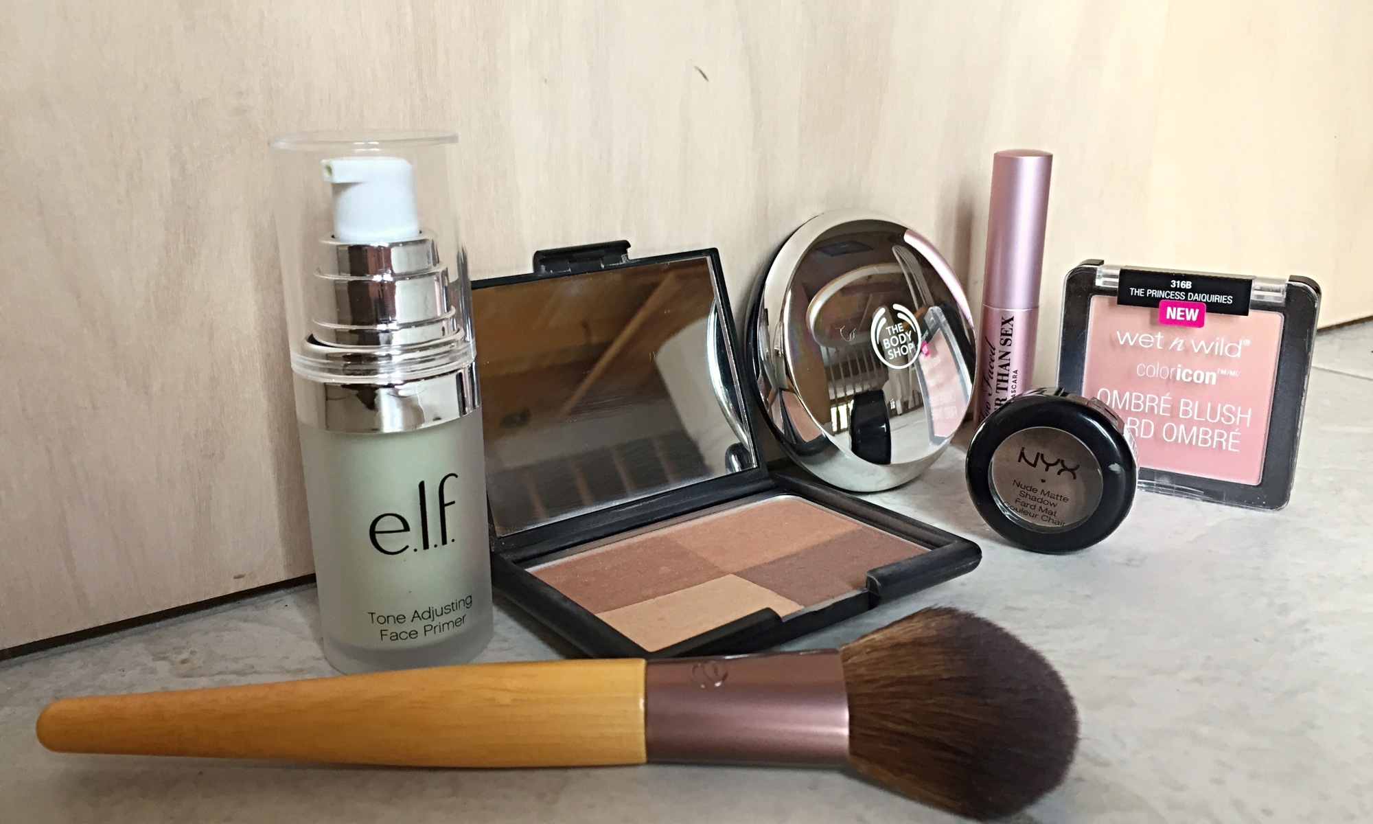 An image of a selection of non-toxic cosmetics, featuring brands such as e.l.f., The Body Shop, Wet N Wild, and Nyx.